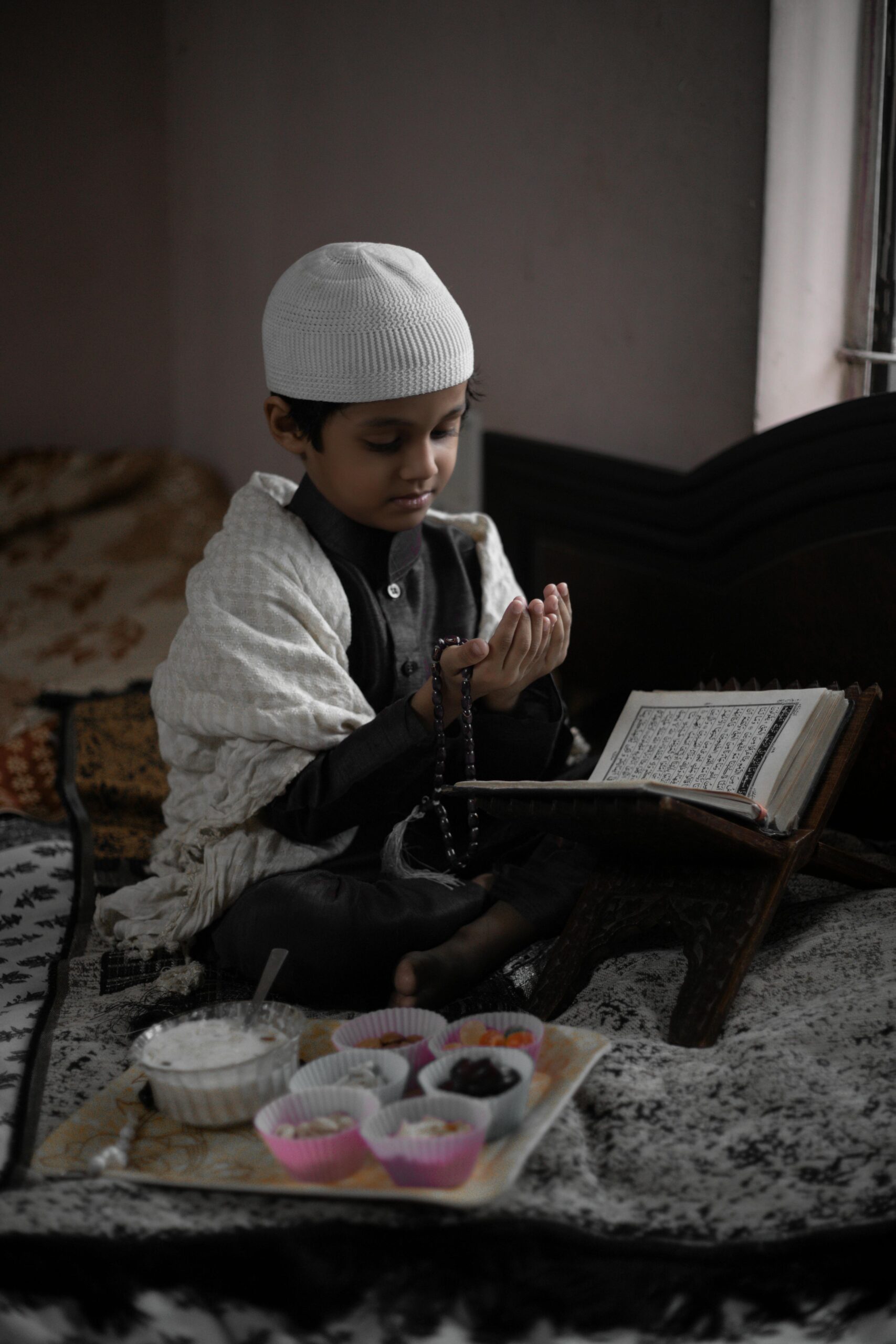 A young boy engaged in studying the Quran indoors, illustrating devotion and education.